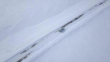 Aerial view on car driving through winter forest road between the snow-covered fields video