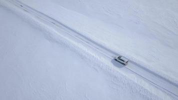 Aerial view on car driving through winter forest road between the snow-covered fields video