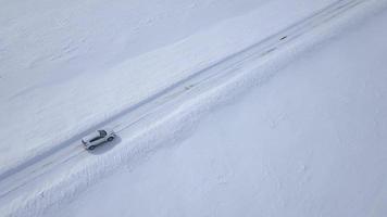 Aerial view on car driving through winter forest road between the snow-covered fields video