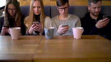 groupe de gens utilisation mobile Téléphone (s dans une café au lieu de communicant avec chaque autre video