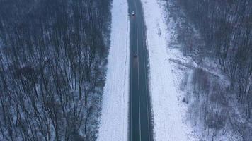 Aerial view on car driving through winter forest road. Scenic winter landscape video