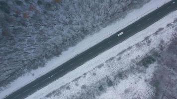 Aerial view on car driving through winter forest road. Scenic winter landscape video