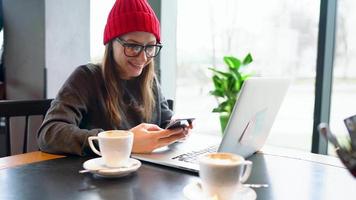 lindo jovem mulher trabalhando e Falando em uma Smartphone dentro uma cafeteria video