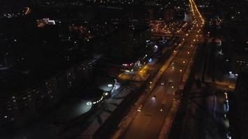 View from the height to the illuminated busy road and night city, multi-storey houses. Ukraine video