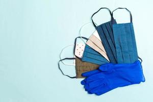 Top view of a heap of homemade cotton masks and nitrile gloves on blue background. Personal protection concept with copy space photo