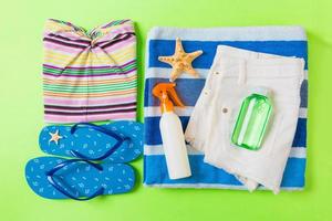 Flat lay composition with blue Beach accessories on green color background. Summer holiday background. Vacation and travel items top view photo