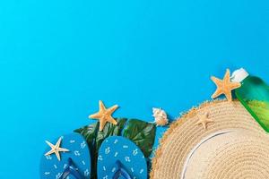 Beach accessories with straw hat and seashells on blue background top view with copy space photo