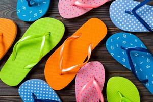 a lot of flip flop colored sandals, summer vacation on wooden background, copy space top view photo