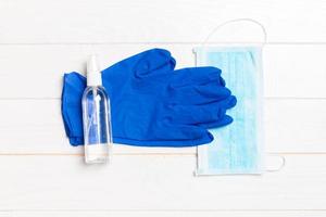 Top view of protective medical equipment such as surgical mask, hand alcohol sanitizer and latex gloves on wooden background. Health care concept with copy space photo