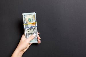 Top view of female hand holding a pack of one hundred dollar bills on colorful background. Wage and salary concept with empty space for your design photo