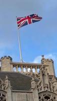 britânico nacional bandeira acenando em construção do parlamento do a Unidos reino. bandeira do ótimo Grã-Bretanha é 1 do Estado símbolos do Estado do a Reino Unido do ótimo Grã-Bretanha e norte Irlanda. vertical vídeo video