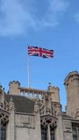 britânico nacional bandeira acenando em construção do parlamento do a Unidos reino. bandeira do ótimo Grã-Bretanha é 1 do Estado símbolos do Estado do a Reino Unido do ótimo Grã-Bretanha e norte Irlanda. vertical vídeo video