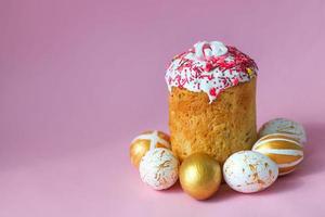 Pascua de Resurrección pasteles - tradicional kulich y dorado huevos en un rosado antecedentes. paska Pascua de Resurrección un pan en ruso letras xb foto