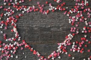 Sweet hearts in the shape of a heart on a wooden background. Frame in the heart of valentines day concept. photo