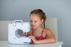 7 years old child studying work with a modern sewing machine. photo