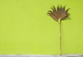 broom on yellow wall background photo