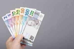 brasileño dinero en el mano en un gris antecedentes foto