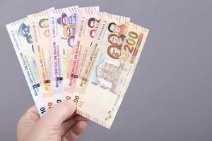 Bolivian money in the hand on a gray background photo