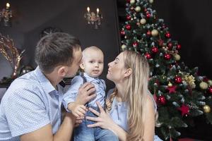 familia a Navidad. madre padre y niño jugar en contra el antecedentes de un Navidad árbol. padres y hijo en el nuevo año. foto