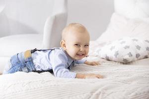 gracioso niño en el cama. un dos año antiguo chico sonrisas foto