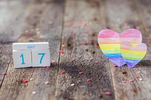 de madera calendario con fecha 17 mayo y corazón pintado en arco iris color. internacional día en contra homofobia, transfobia y bifobia lgbt. foto