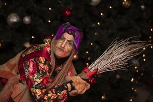 Baba Yaga with a broom on the background of the Christmas tree.Russian witch. photo