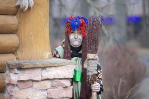 Baba Yaga with a broom near a wooden hut. photo