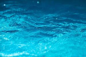 Close-up of blue water in the pool. Side view. Bokeh light background in the pool. photo