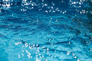Close-up of blue water in the pool. Side view. Bokeh light background in the pool. photo