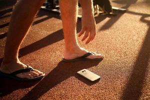 The man found the phone. Male hand reaches out to lift a smartphone from the ground. photo