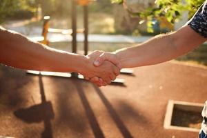 Male handshake in the street against the background of the sports ground. photo