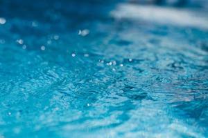 Close-up of blue water in the pool. Side view. Bokeh light background in the pool. photo