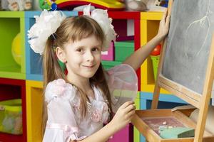 Girl preschooler. Primary school student at the blackboard. photo