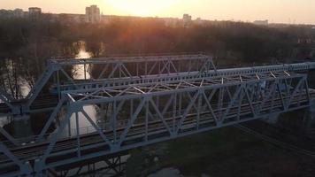 Visão a partir de a altura do a estrada de ferro ponte em que a trem é passagem às pôr do sol video