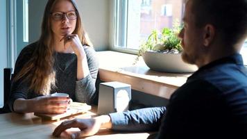 Young couple talking and drinking coffee in cafe video