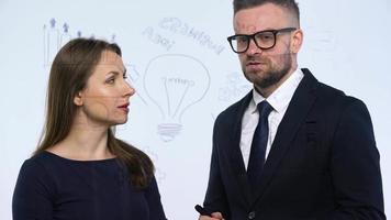 Man and woman discuss the business strategy for success in a modern glass office video
