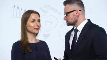 Man and woman discuss the business strategy for success in a modern glass office video