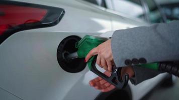 Woman inserts a fuel gun in a gas tank to refuel a car video