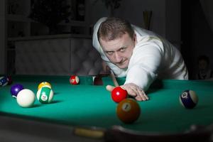 A man plays billiards. A man with a cue in his hands. photo