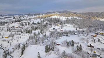 Flight over snowy mountain village and coniferous forest. Clear sunny frosty weather video