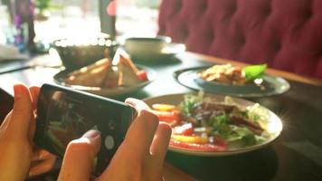 fille fait du une photo de repas sur une téléphone intelligent dans une café proche en haut video