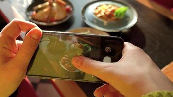 Mädchen macht ein Foto von Mahlzeit auf ein Smartphone im ein Cafe schließen oben video
