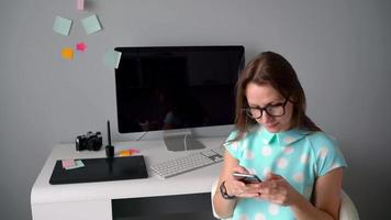 Casual graphic designer talking on the phone during a coffee-break in creative office video