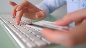 Woman pays by credit card purchases on the Internet. Woman office worker typing on the keyboard. Online payment concept video