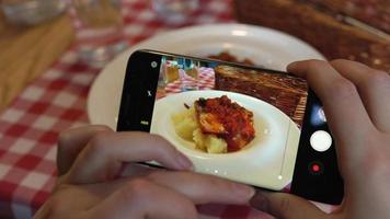 niña hace un foto de comida en un teléfono inteligente en un café cerca arriba video