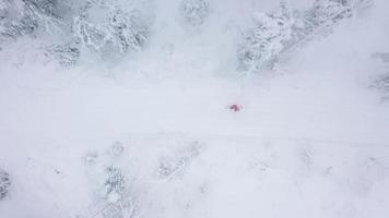 se från höjd till man är ridning en snowboard på en snötäckt fält på en kabel- Bakom en bil video