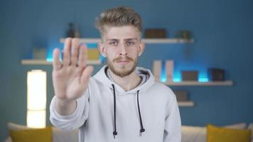 The young man, who raises his hand and makes a stop sign, shakes his head with a negative expression. video