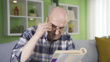 Defect of vision. The old man is wearing glasses. The old man reading a book wears glasses due to visual impairment. video