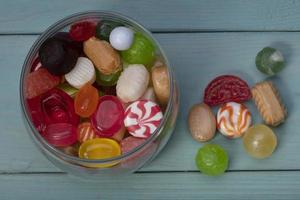 Candies in a jar on a blue background. Multi-colored caramel on a wooden board. Sweets. photo