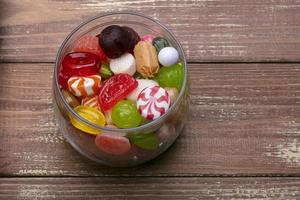 Candies in a jar on a wooden background. Multi-colored caramel. Sweets. photo